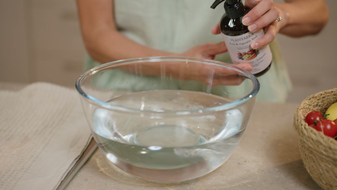 A hand pumping Plantaera into a glass bowl of water