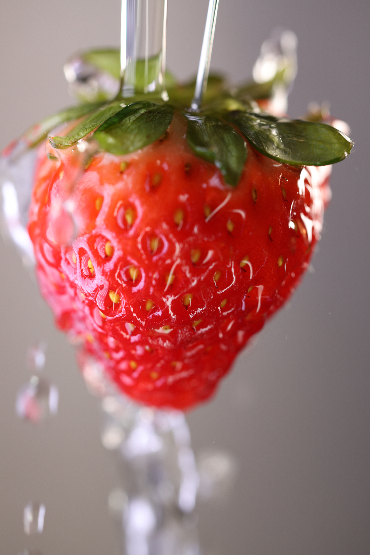 A fresh strawberry being rinsed under a clear stream of water