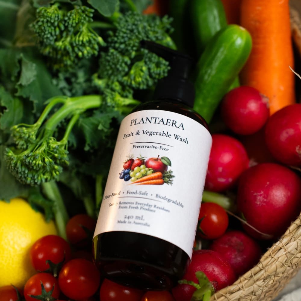 A Plantaera bottle resting in a basket of lemons, broccoli, tomatoes and radishes
