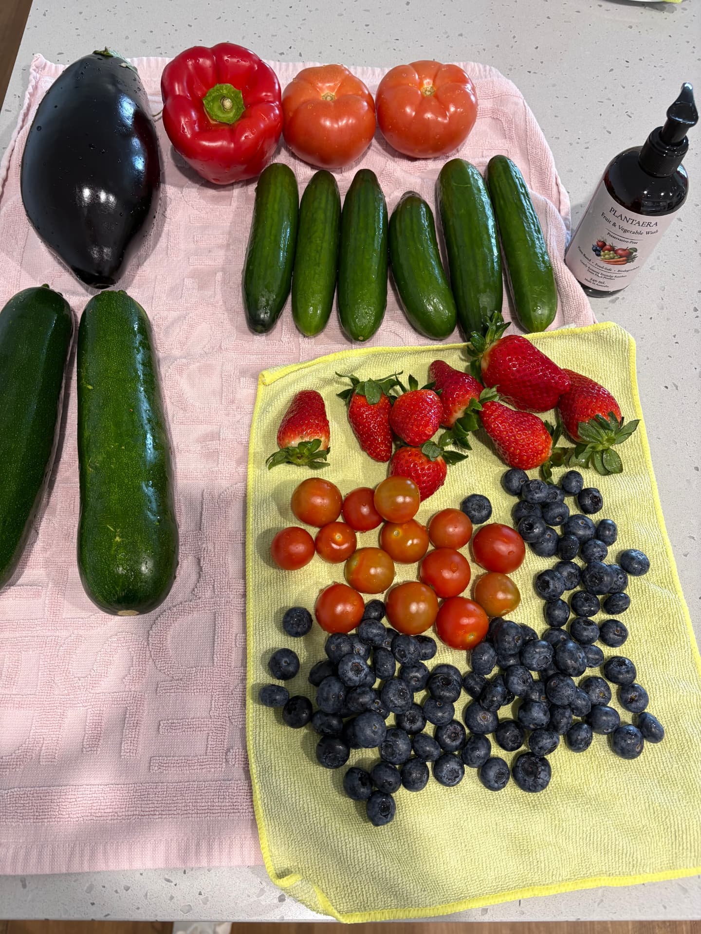 Freshly washed produce arranged on a kitchen counter with a Plantaera bottle