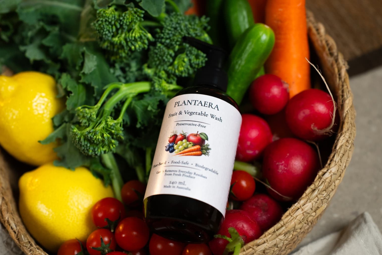 A Plantaera bottle resting in a basket of lemons, broccoli, tomatoes and radishes