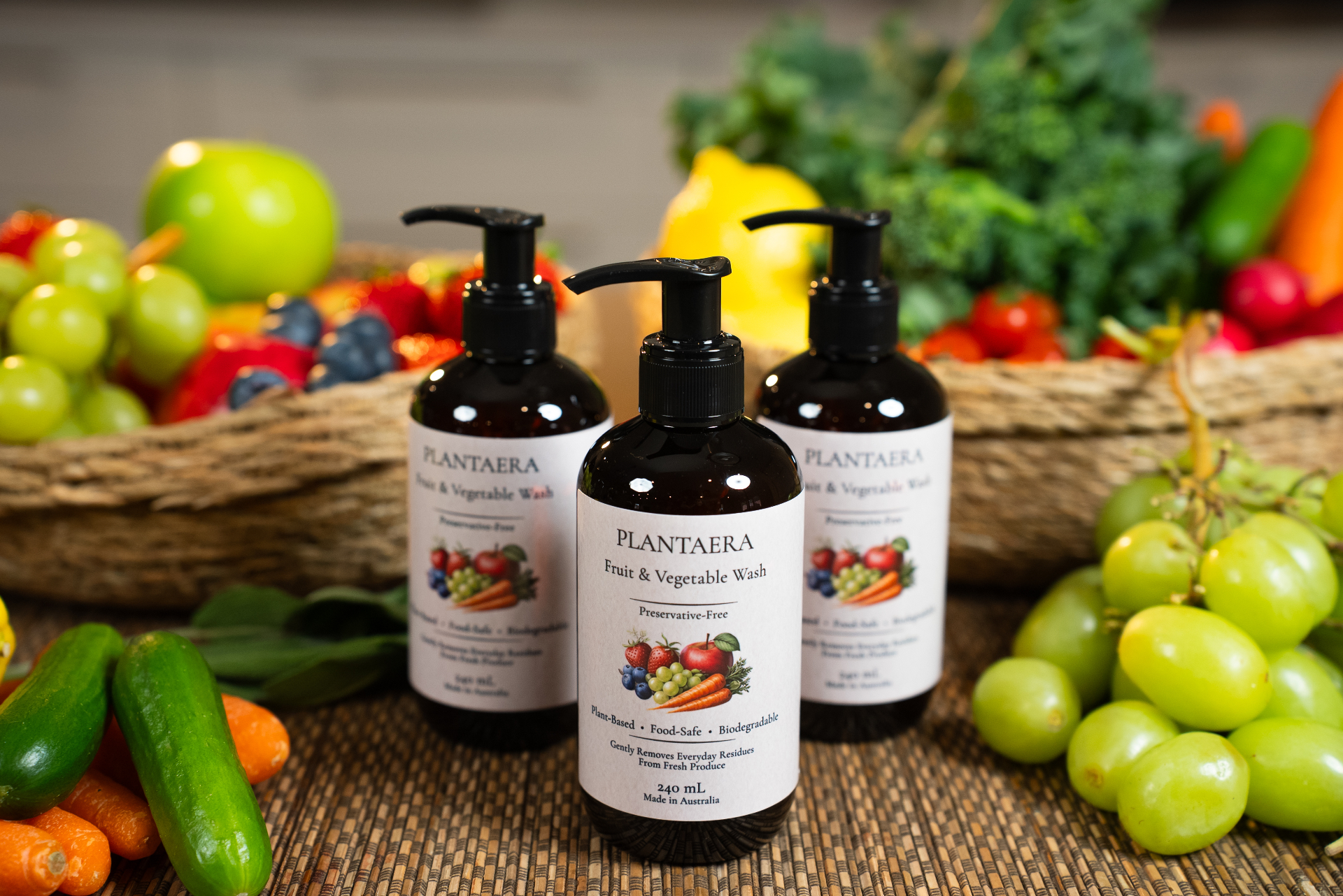 Three Plantaera fruit and vegetable wash bottles surrounded by fresh produce