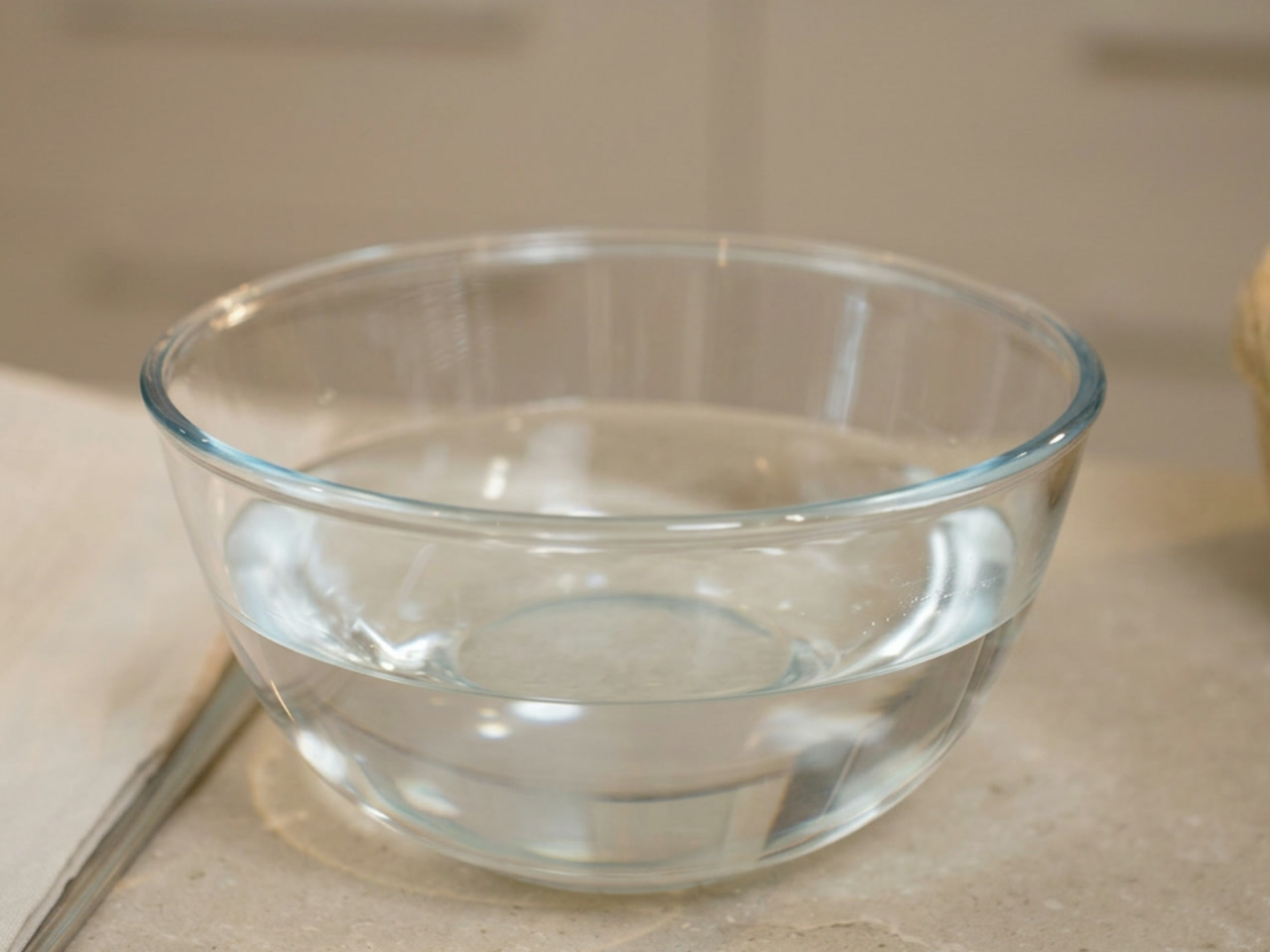 A glass bowl filled with cool, fresh water on a kitchen counter