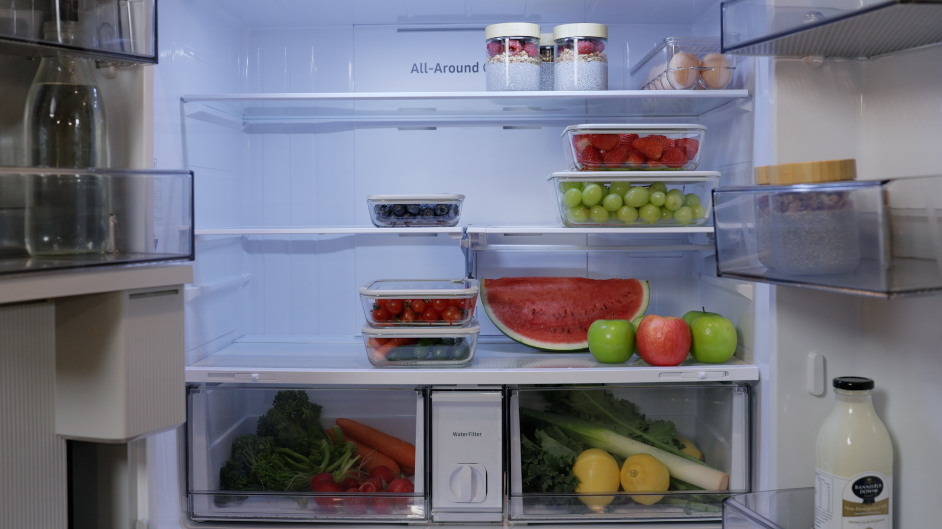An organised fridge of washed fruit and vegetables in glass containers